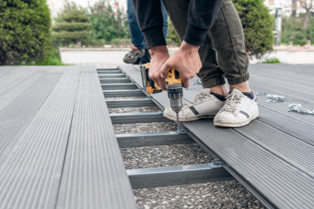 Worker assembling composite deck using cordless screwdriver